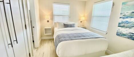 A bedroom with a bed, bedside tables, a wardrobe, and a painting on the wall.