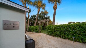 A sign indicating beach access, a gravel path, and a hedge. - Amazing NEW 1BR APT just Steps to the Beach! Unit 312 (Cocoa Beach)