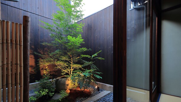 A traditional Japanese garden with a small tree, rocks, and a wooden fence. - Houka (Kyoto)