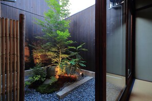 Un jardin japonais traditionnel avec un petit arbre, des rochers et une clôture en bois.