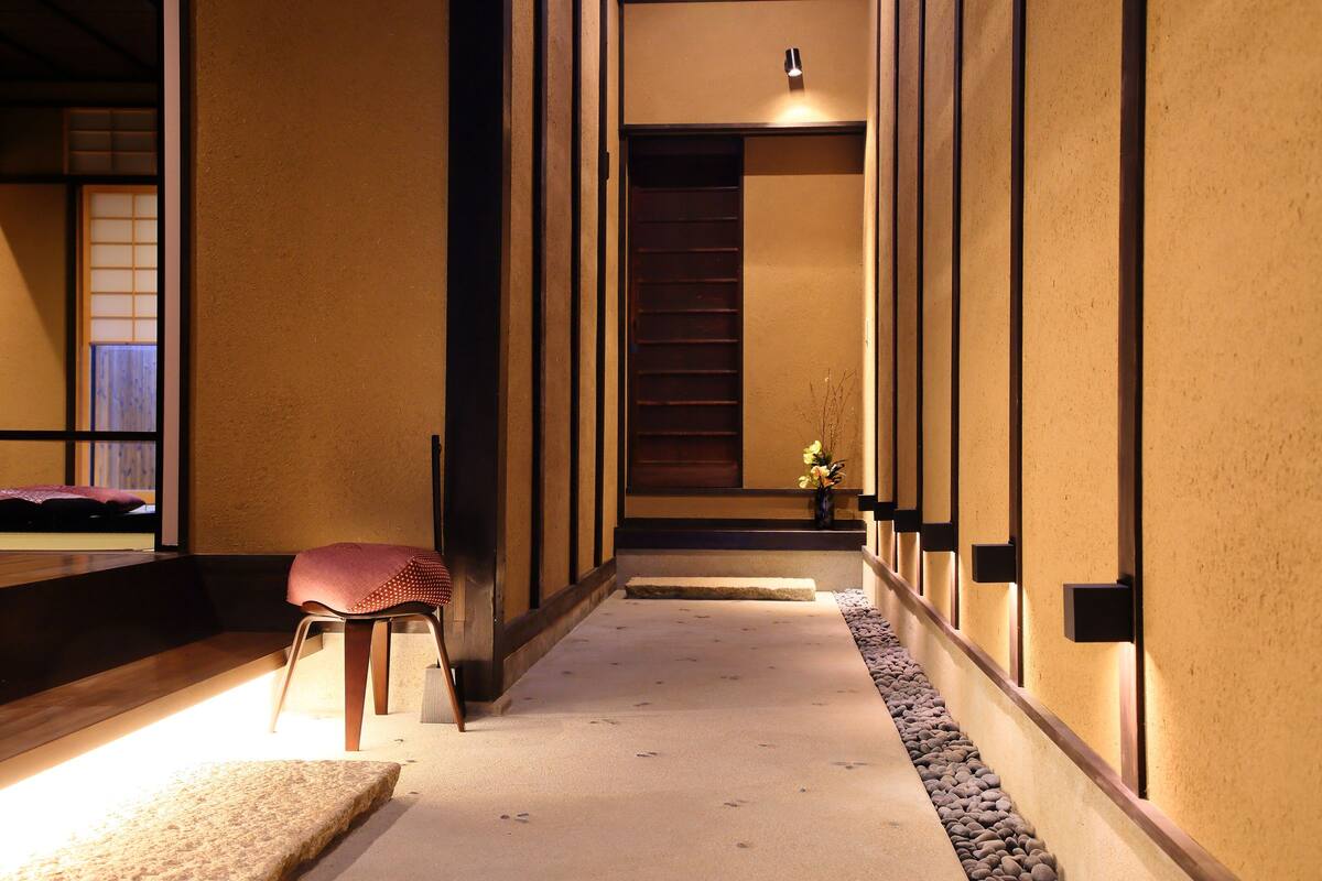 Un pasillo con un banco de madera, una mesita con un florero y una escalera que lleva a una habitación.
