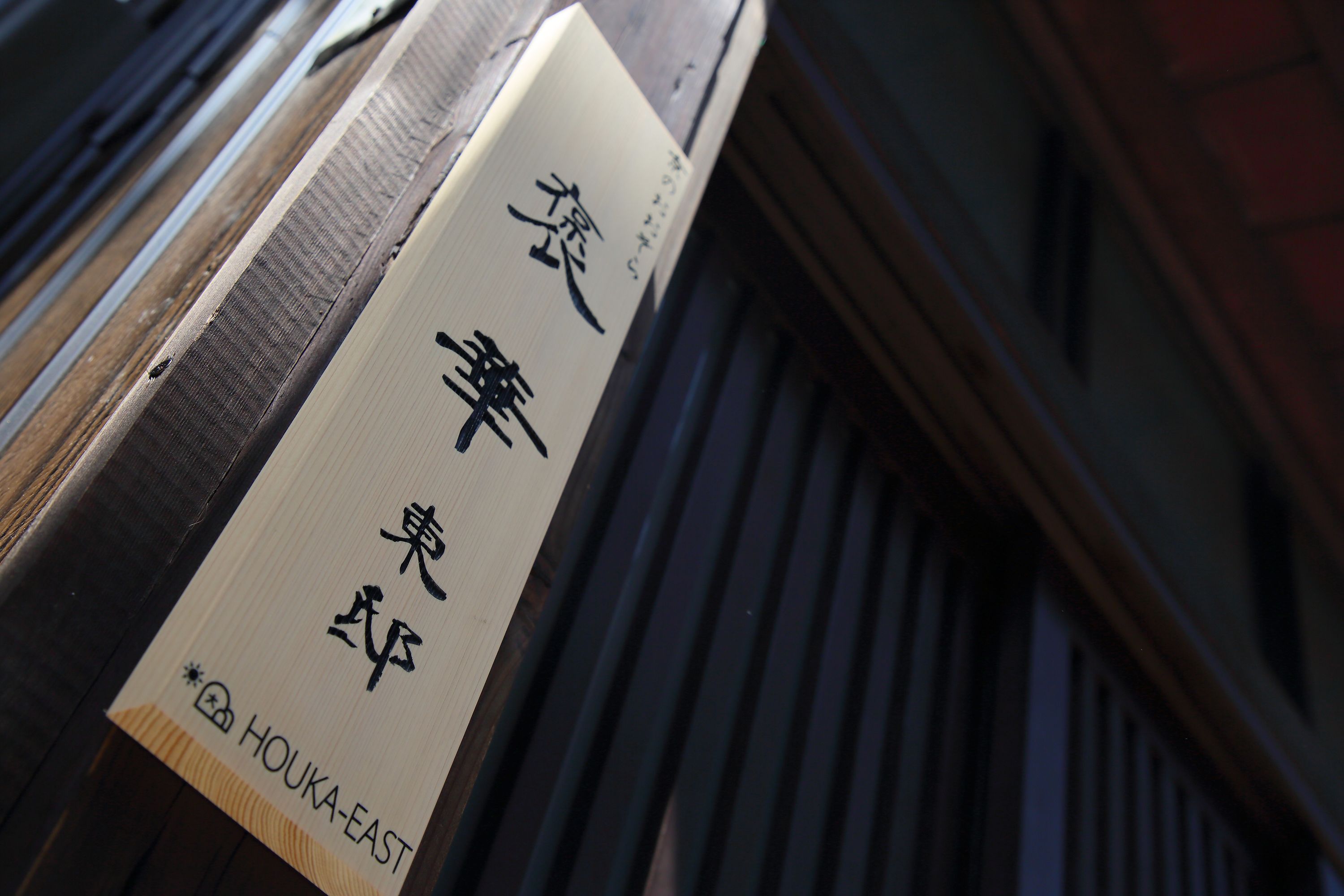A wooden sign with Japanese characters and the name "HOUKA-EAST" at the bottom.