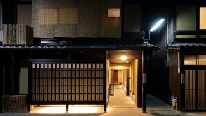 A traditional Japanese building with a wooden exterior, a covered entrance, and a narrow corridor leading to a room. - Houka (Kyoto)