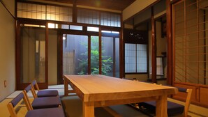 A traditional Japanese room with tatami flooring, a wooden table, and low cushions. - Houka (Kyoto)
