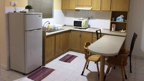 Une cuisine compacte avec des meubles de rangement en bois, un réfrigérateur, un four à micro-ondes et une table à manger avec des chaises.