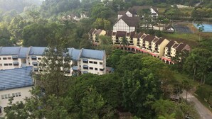 Un hôtel composé de plusieurs bâtiments à étages, doté d’un parking et entouré d’une végétation luxuriante.