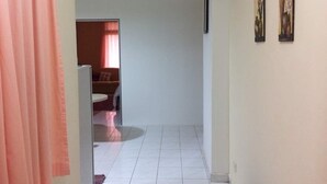 Un couloir au sol carrelé, une porte sur la gauche et un mur orné de deux tableaux encadrés.