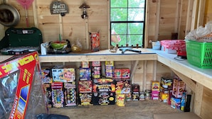 A rustic cabin interior with wooden walls, a window, shelves with various items, and a bench. - Peaceful lakeside private waterfront campsite; 45 min drive to Acadia! BYOTent (Eastbrook)