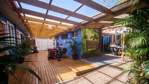 A covered patio area with wooden flooring, potted plants, and a mural on the wall. - Ozzie Pozzie Backpackers (Port Macquarie)