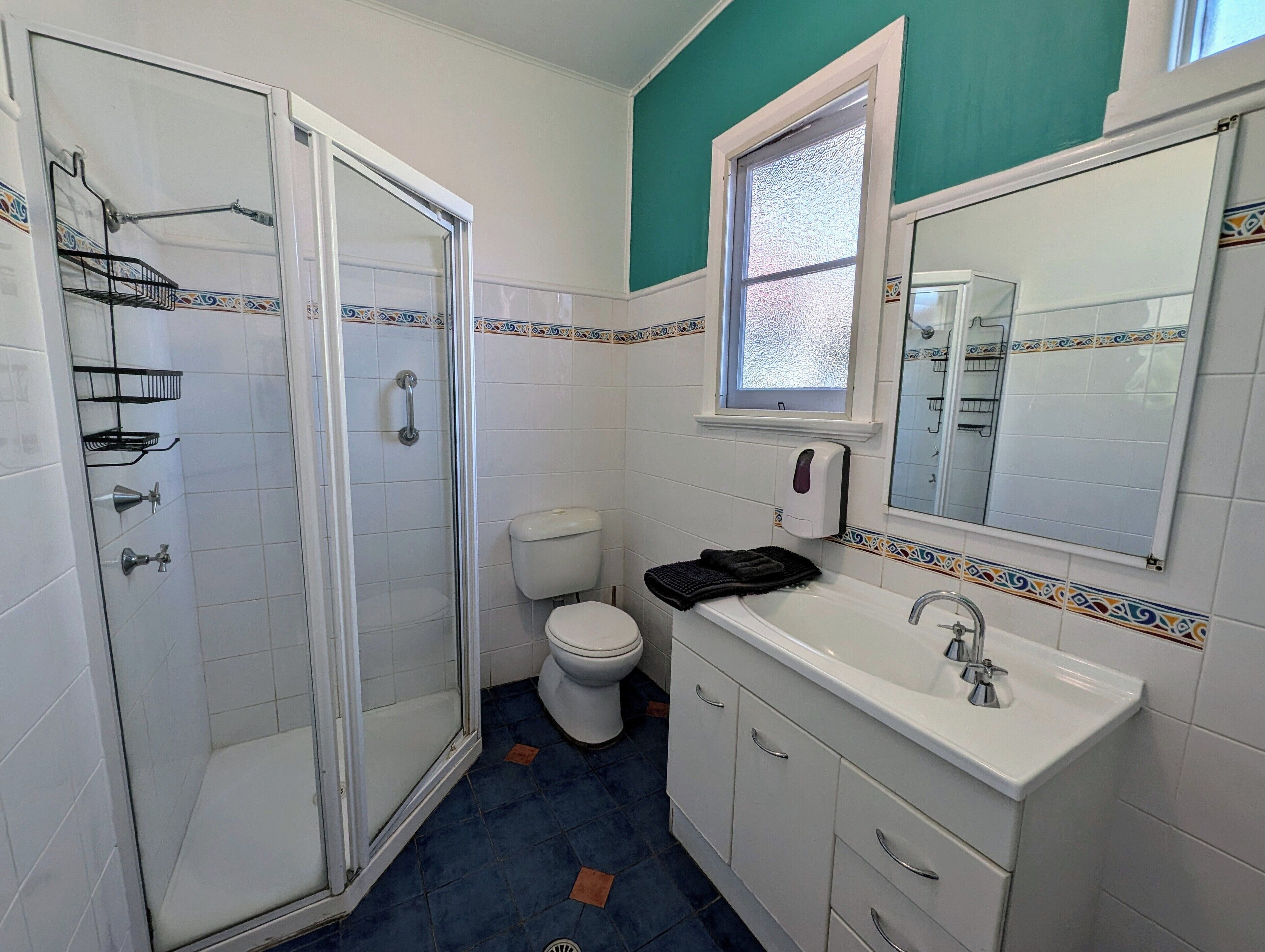 Baño con ducha, inodoro, lavabo y ventana.