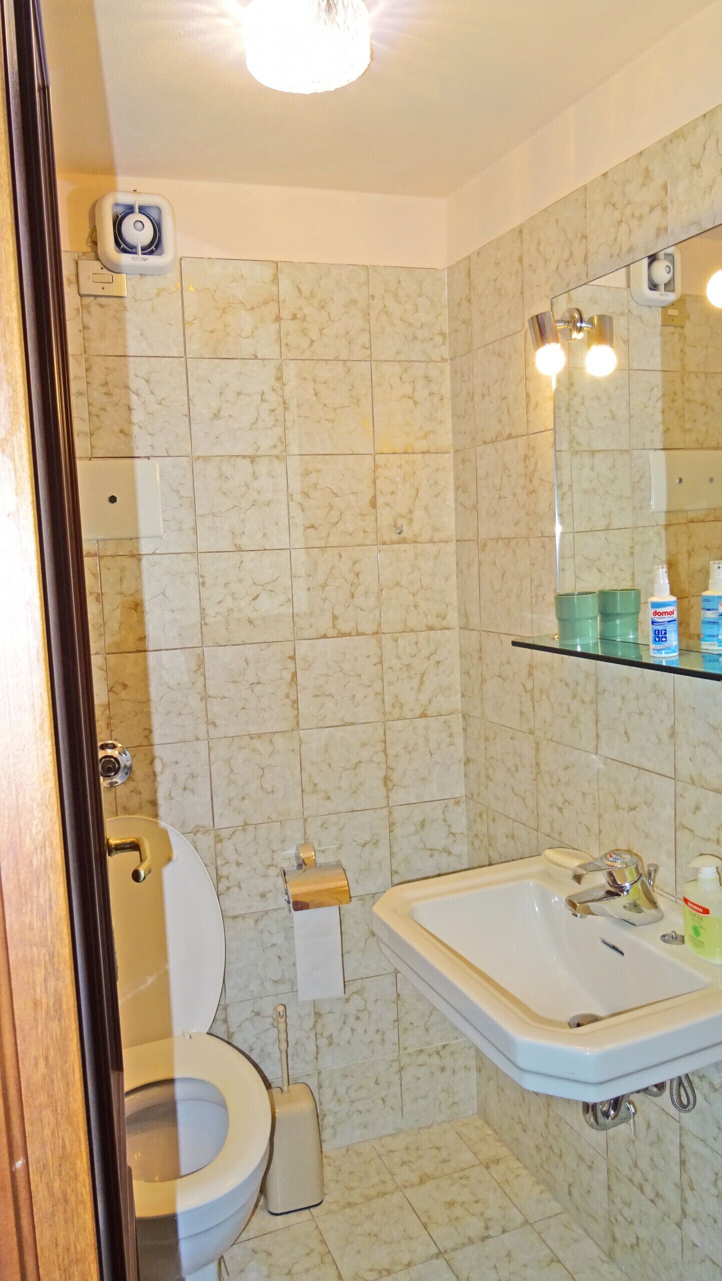 A bathroom with a toilet, sink, and mirror.
