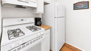 Une cuisine avec un four blanc, une machine à café et un réfrigérateur.