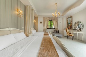 Habitación de hotel con dos camas, un escritorio, una silla, una araña y un espejo grande en la pared.