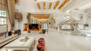 A spacious living room with a high ceiling, a staircase, and a fireplace. - Pass Happiness On (Wujie)