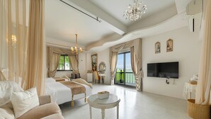 A spacious hotel room with a large bed, a sofa, a small round table, a TV, and a balcony with curtains. - Pass Happiness On (Wujie)
