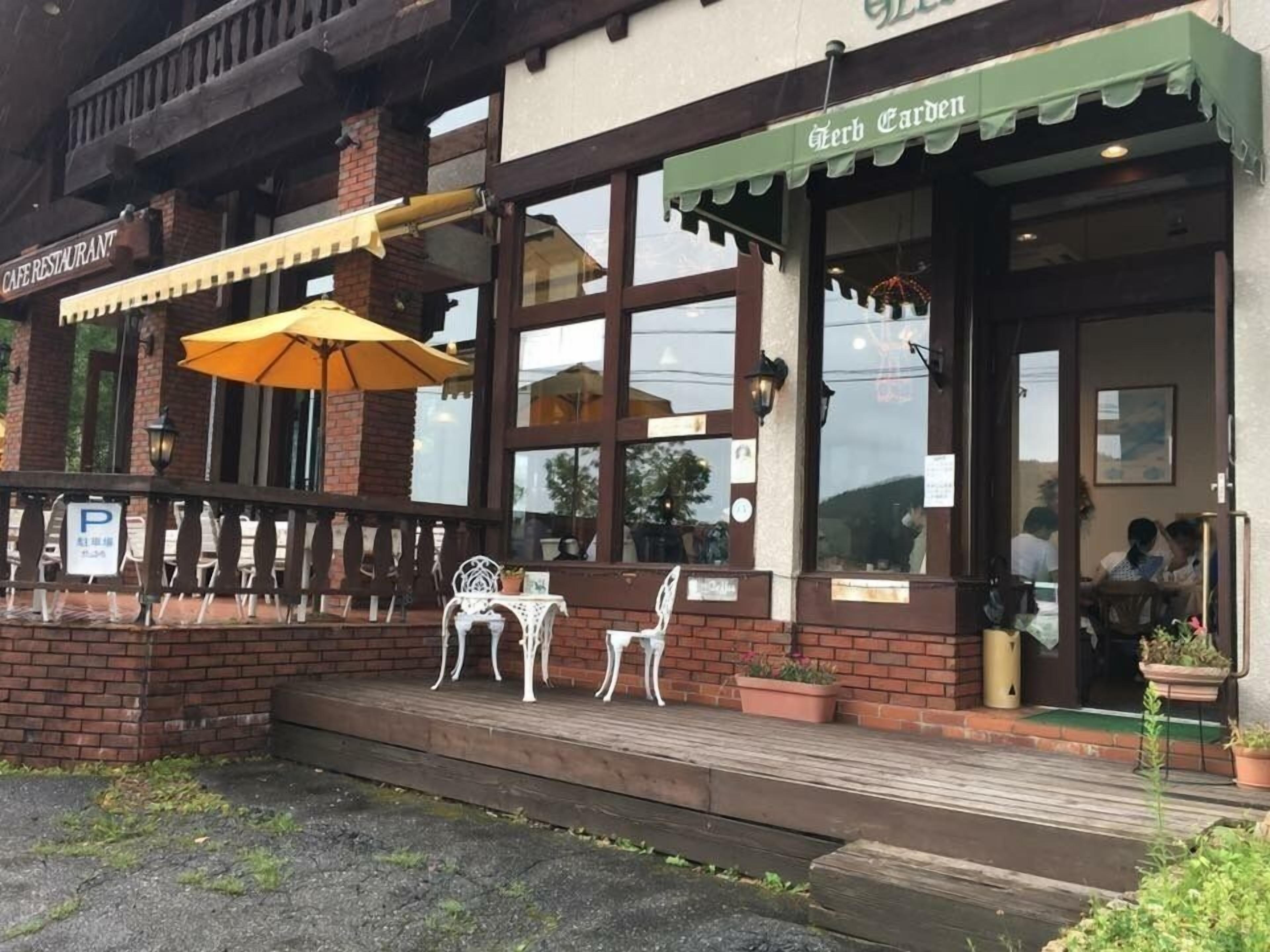 A cafe with outdoor seating, a green awning, and a brick facade.