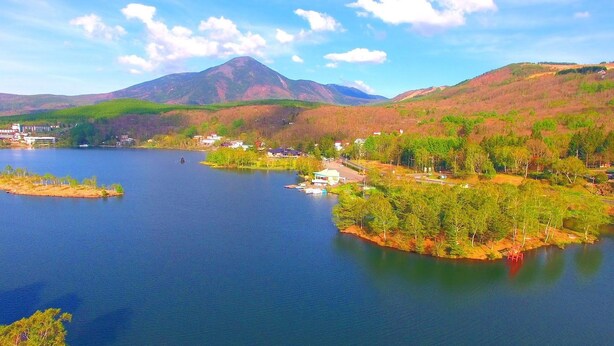 A lake with a small island, a mountain in the background, and a few buildings on the shore.
