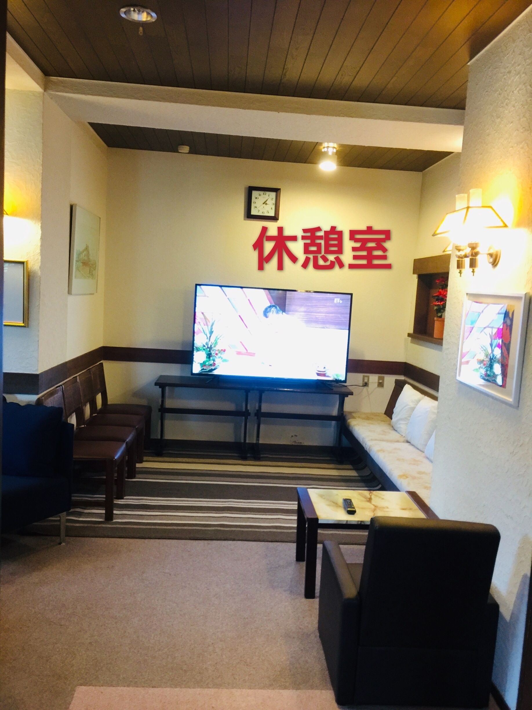 A hotel room with a television, a sofa, a bed, and a small table.