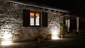 Un bâtiment en pierre avec une fenêtre en bois et deux plantes en pot ornées de fleurs rouges.