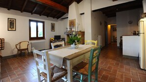 Un coin repas avec une table et des chaises en bois, un radiateur blanc et une fenêtre donnant sur un paysage agréable.