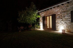 Ein Steinhaus mit einer Holztür und einer kleinen Außenbereich-Sitzgelegenheit mit Stühlen und einem Tisch.