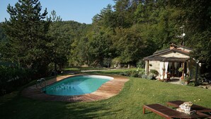 Une piscine dotée d’une terrasse en bois, entourée d’une pelouse bien entretenue et d’arbres.