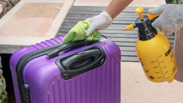 A purple suitcase being cleaned with a green cloth and a yellow spray bottle.