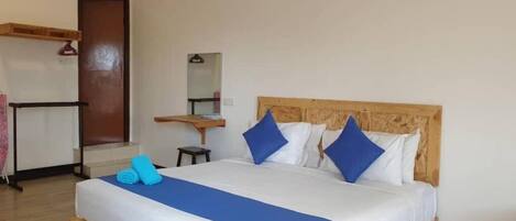 A neatly made bed with blue and white bedding, a wooden headboard, and a small bedside table with a mirror.