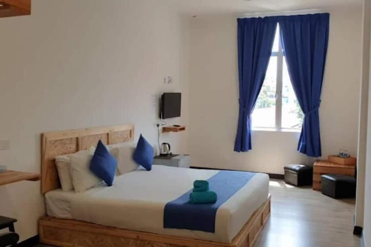 Una camera da letto con un letto, un comodino, una TV e una finestra con tende.