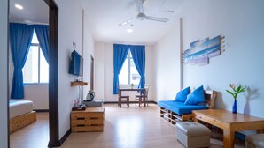 Una sala moderna con sofá, reposapiés, mesa de centro de madera y televisor sobre un mueble.