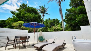 Un patio con una mesa y sillas, una silla colgante, una sombrilla y un jacuzzi.
