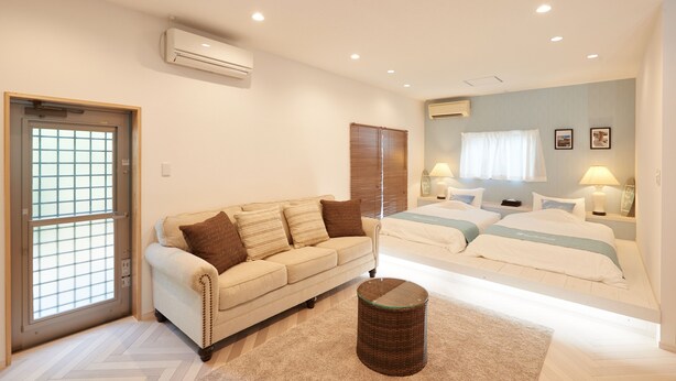 Un dormitorio con sofá, cama, mesita de noche y lámpara.