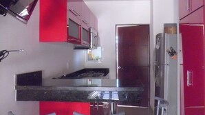 Une cuisine moderne dotée d’un îlot central, d’appareils électroménagers en acier inoxydable et de touches de couleur rouge.