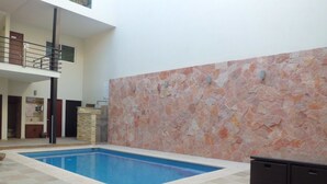 Une piscine intérieure avec un mur en pierre et un sol carrelé.