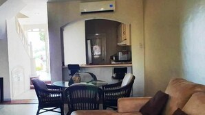 A living room with a sofa, a dining table with chairs, and a kitchen area with a refrigerator and microwave. - Condo P Iguana (Mazatlán)