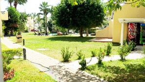 A courtyard with a pool, palm trees, and lounge chairs. - Condo P Iguana (Mazatlán)