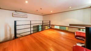 A spacious room with a wooden floor, a black metal railing, and red chairs. - Blue Motel (Boryeong)