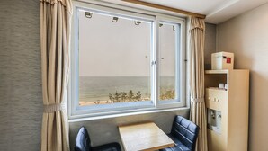 A room with a large window, two black leather chairs, a small wooden table, and a cabinet with a red label. - Blue Motel (Boryeong)