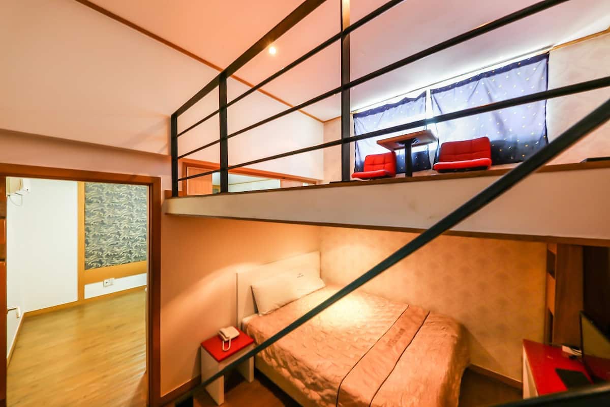 Una habitación pequeña con literas, un escritorio y una ventana con cortinas.