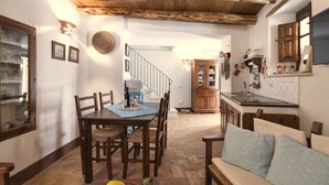 Ein Essbereich mit Holztisch und -stühlen, eine Küche mit Holzschränken und eine Treppe, die zu einer anderen Ebene führt.