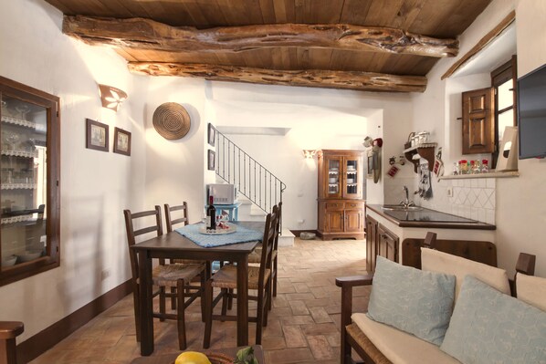 A dining area with a wooden table and chairs, a kitchen with wooden cabinets, and a staircase leading to another level.