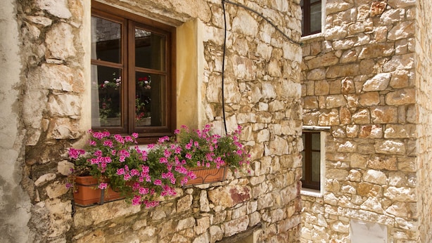 Ein Steinhaus mit Fenster und Blumenkästen.