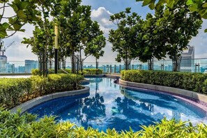 A rooftop pool with surrounding greenery and a cityscape view. - The Robertson 1 Bedroom Bukit Bintang KL (Kuala Lumpur)