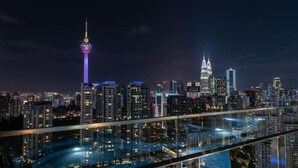 A nighttime cityscape with a prominent tower and a distinctive building with three spires. - The Robertson 1 Bedroom Bukit Bintang KL (Kuala Lumpur)
