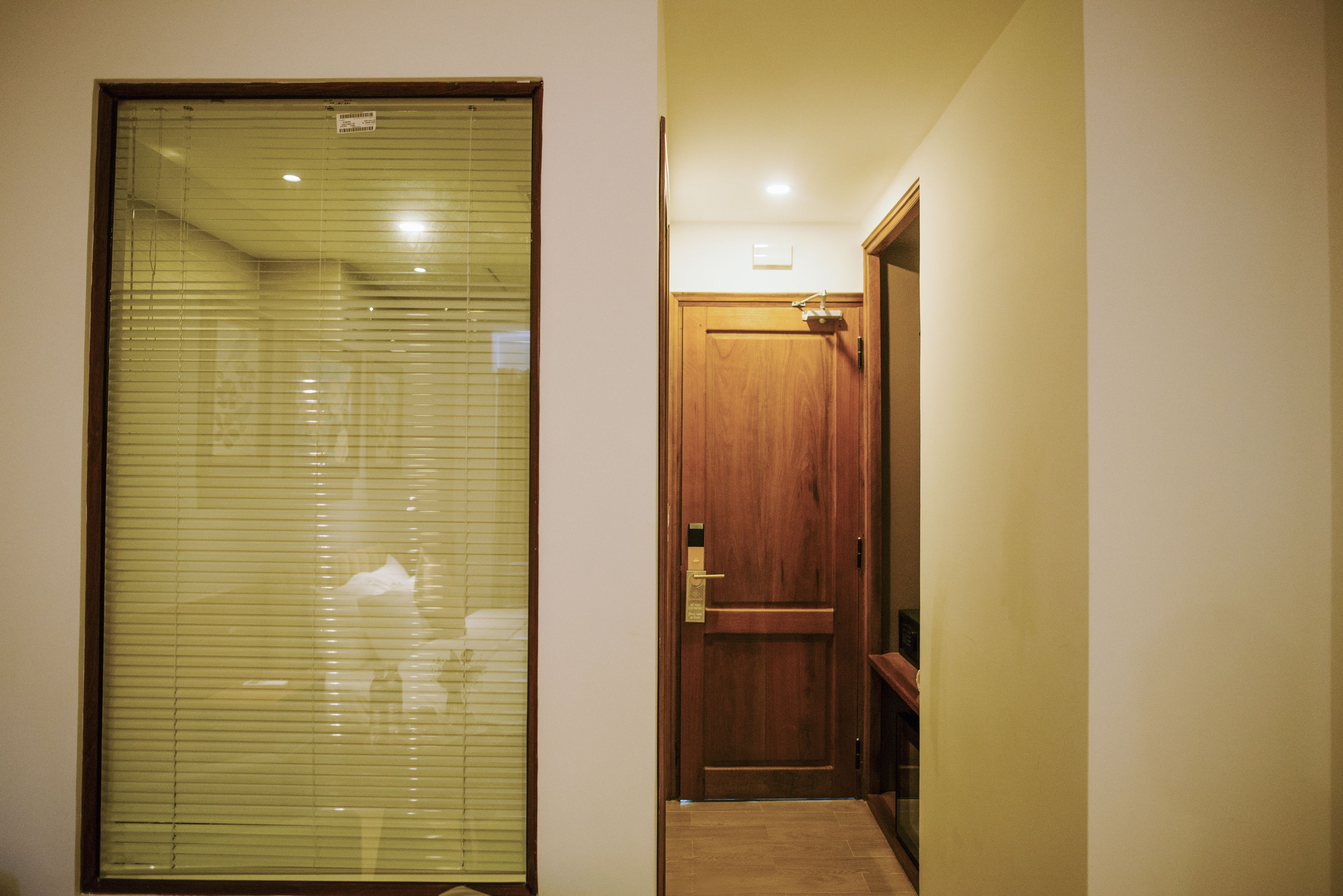 A hallway with a wooden door and a window with blinds.