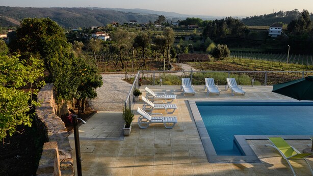 A pool area with lounge chairs, a stone pathway, and a view of the countryside. - Casa da Caneleira (Camélias de Basto) (Codeçoso)