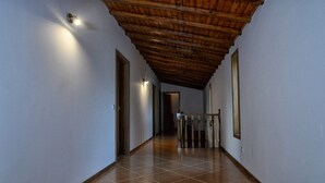 A hallway with a wooden ceiling, tiled floor, and wall-mounted lights. - Casa da Caneleira (Camélias de Basto) (Codeçoso)