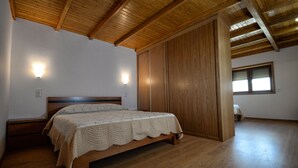 A bedroom with a wooden bed, wooden walls, a sloped ceiling, and a window with blinds. - Casa da Caneleira (Camélias de Basto) (Codeçoso)