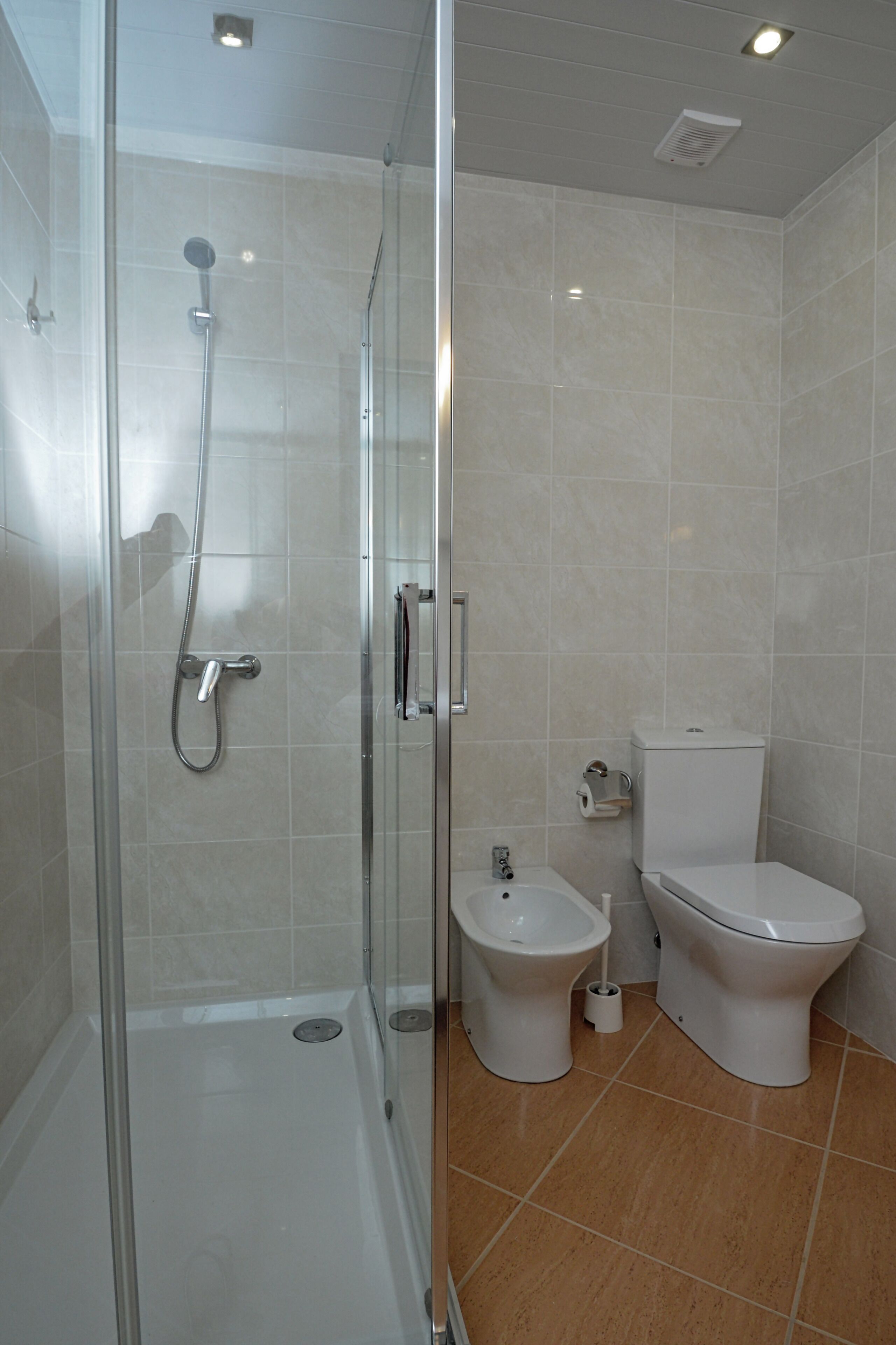 A bathroom with a glass-enclosed shower, a toilet, and a bidet.