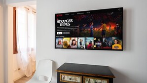 Eine Netflix-Oberfläche auf einem an der Wand montierten Bildschirm, die 'Stranger Things' zeigt.